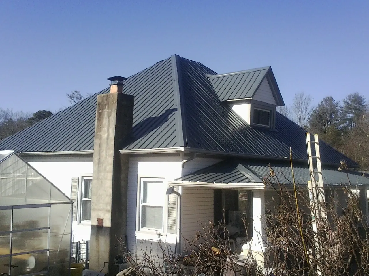 Dark blue standing seam metal roof on a white farmhouse with dormer in Cocoa Beach