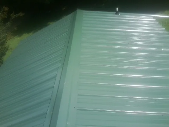 New green metal panels meeting at the ridge of a roof — Flat Roof Repair work by our crew in Cocoa Beach