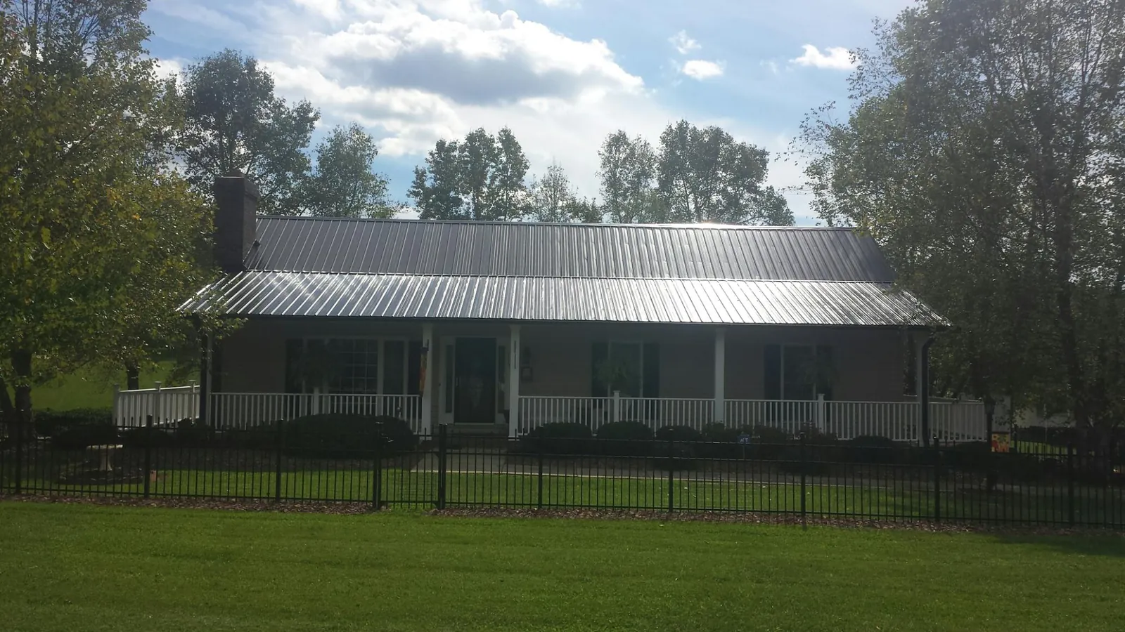 Gray metal roof on a brick ranch with a full width front porch — Gutter Guard Installation work by our crew in Cocoa Beach