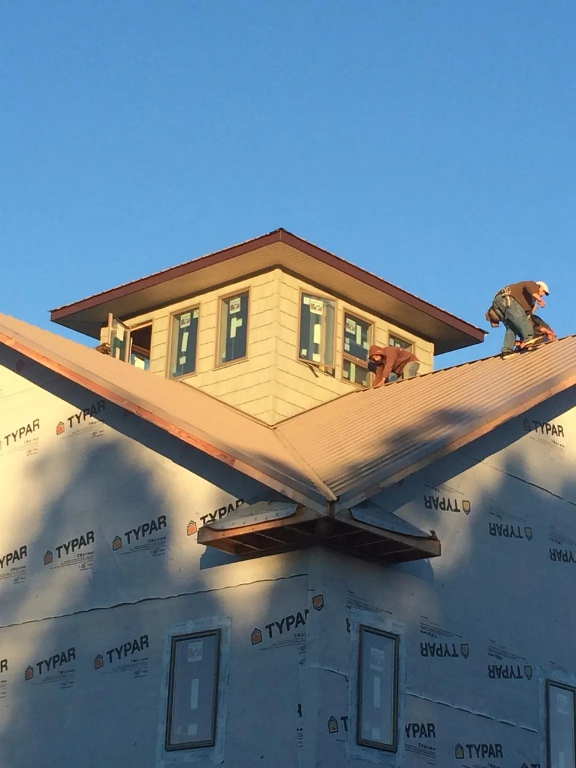Roofers working around a rooftop cupola on a new metal roof at sunset — Roof Waterproofing in Cocoa Beach by Roofing Brothers